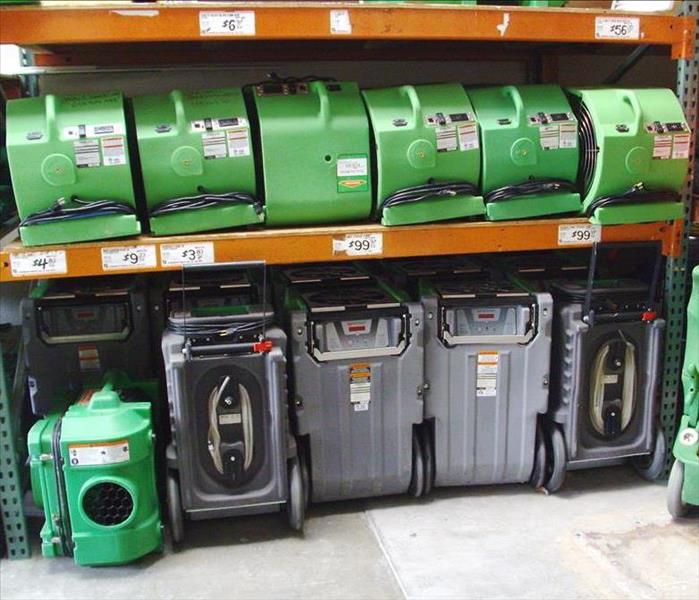 air movers and dehumidifiers in a warehouse stacked on racks organized neatly