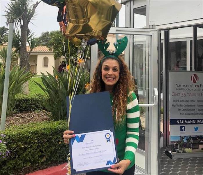 woman curly long hair green christmas sweater holding certificate award and balloons